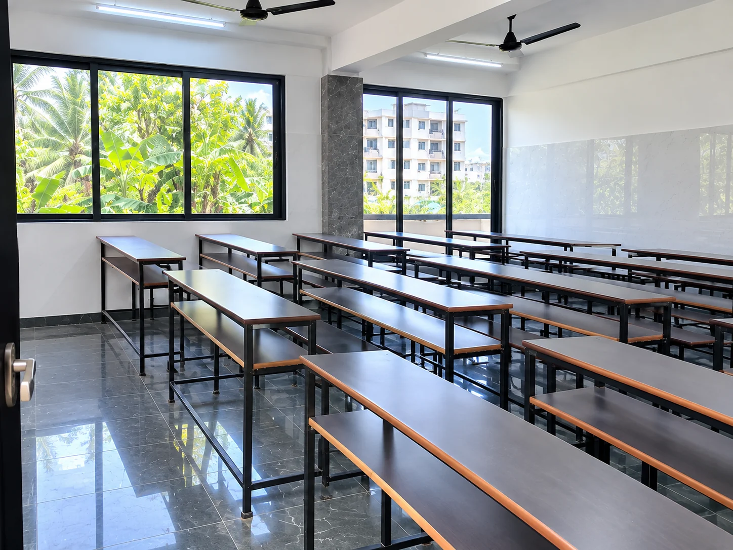 Bright classroom with large windows and rows of study benches