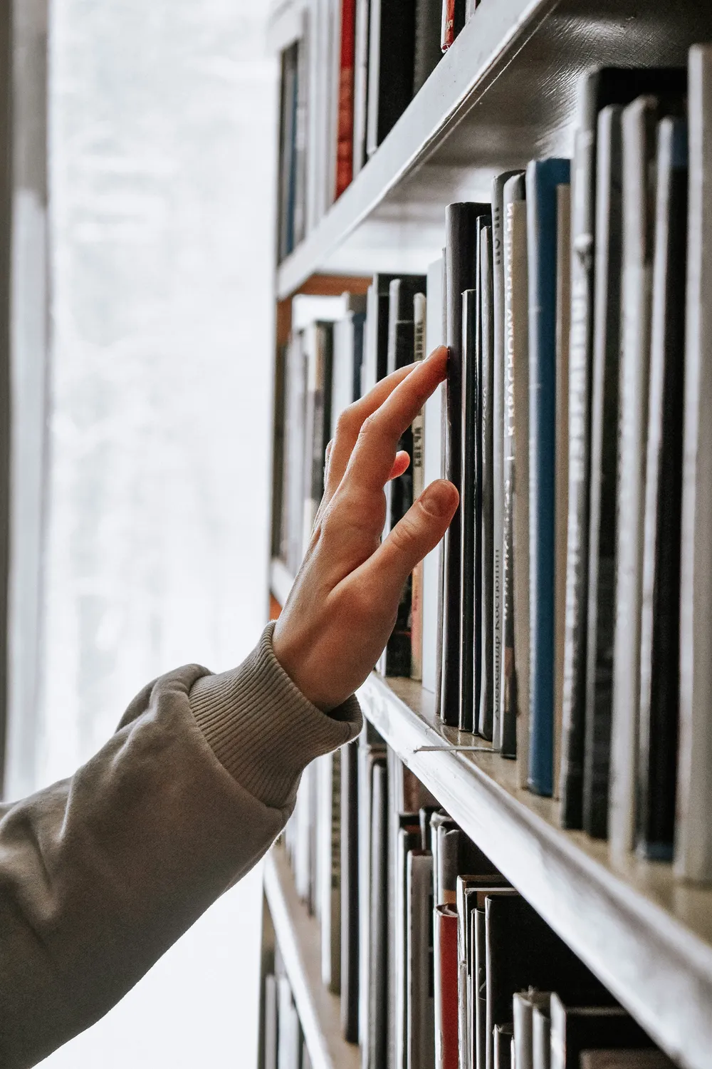A student choosing a book from the library shelves
